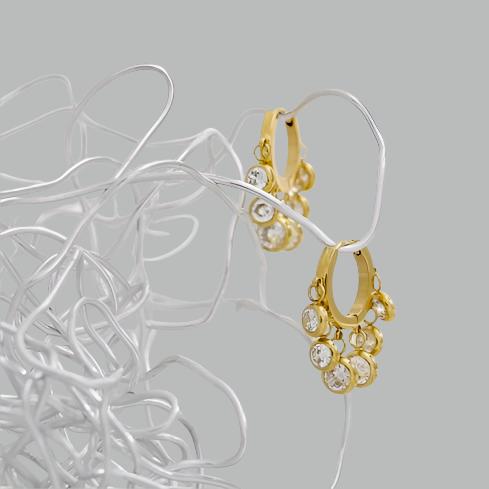 Pair of hoop earrings with clear gemstones hanging on silver wire on a grey background
