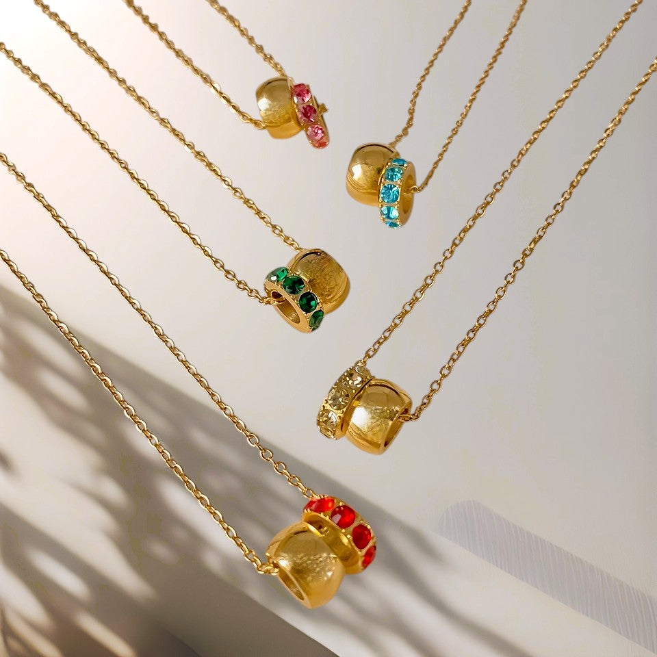 Gold necklaces with colorful pendant beads on a neutral background