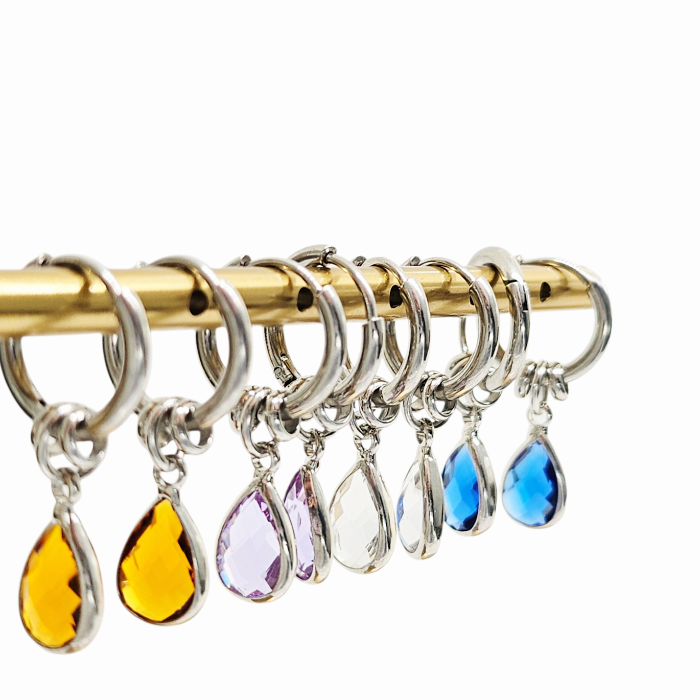 Set of colorful teardrop-shaped keychains on a gold rod against a white background