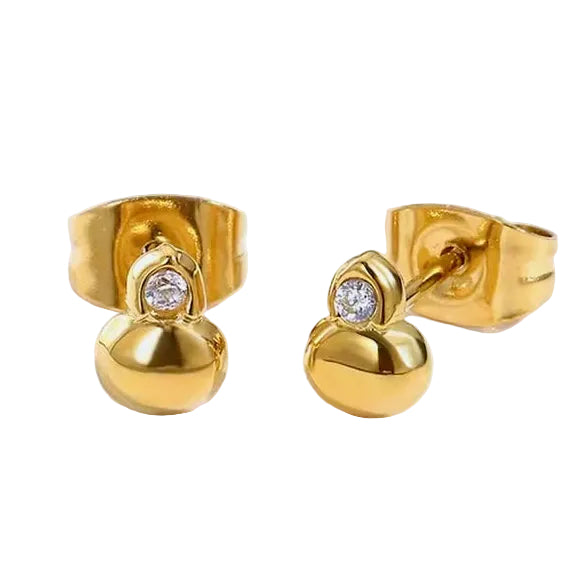 A pair of gold stud earrings with a small round clear gemstone and a larger polished gold bead drop, shown on a light gray background.