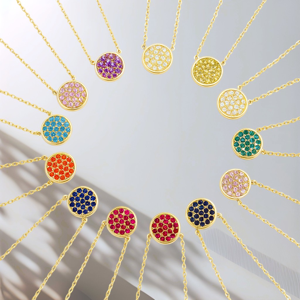 Gold necklaces with colorful gemstones on a light gray background