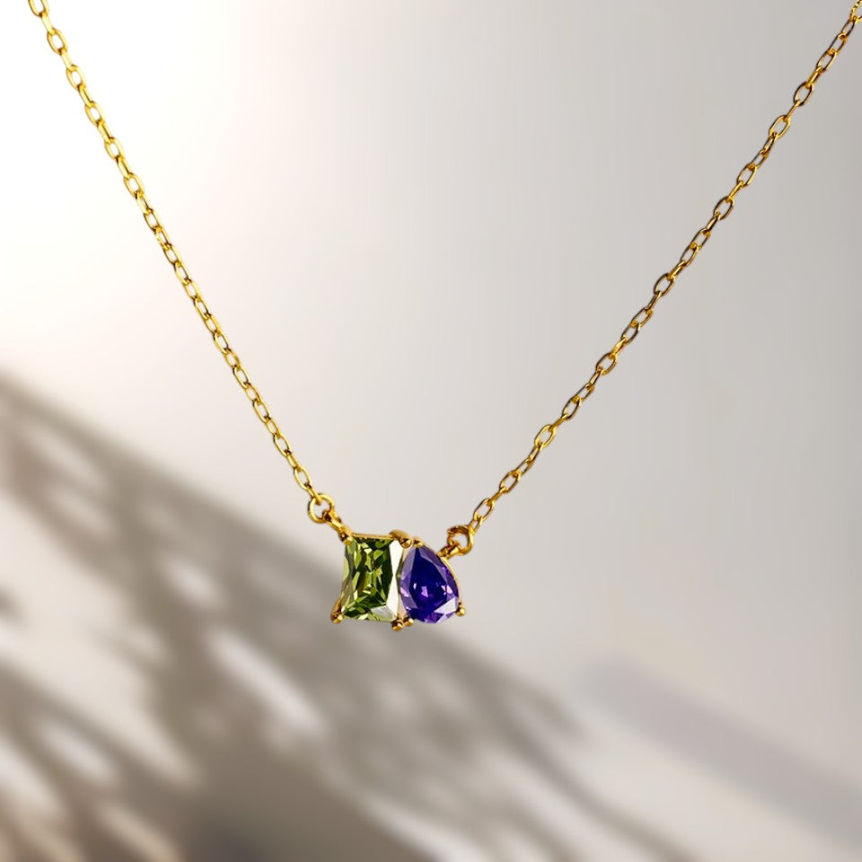 Gold necklace with two gemstones on a neutral background