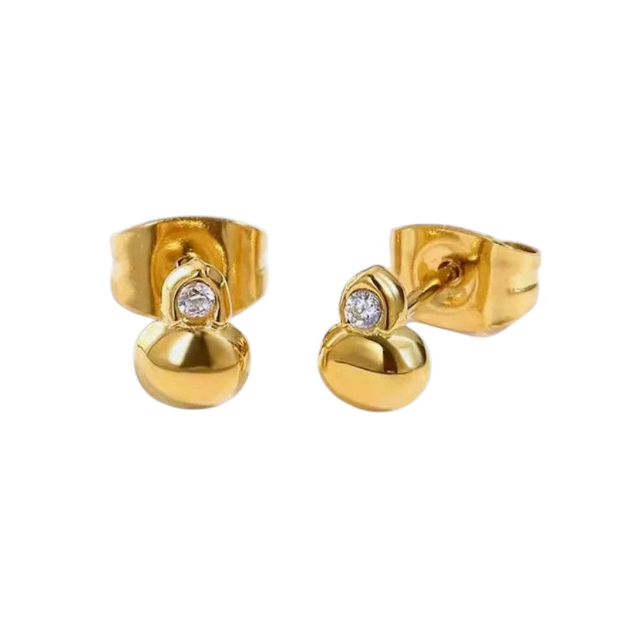 A pair of gold stud earrings featuring a polished dome-shaped bead with a small round clear gemstone at the top, set in a textured gold post with a flat back.