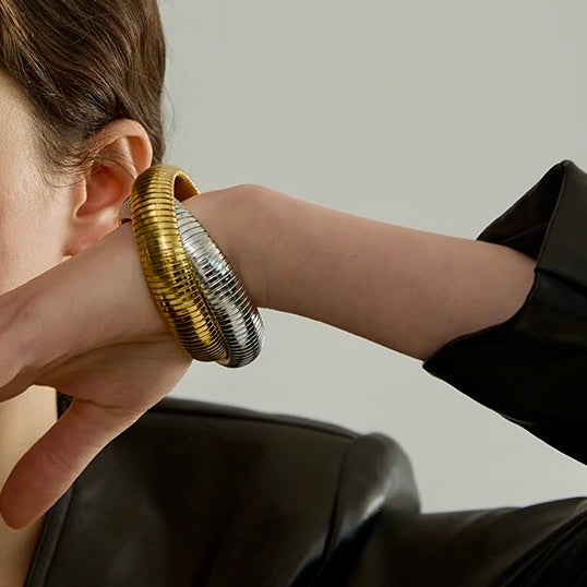 Person wearing a gold and silver hoop earring against a neutral background