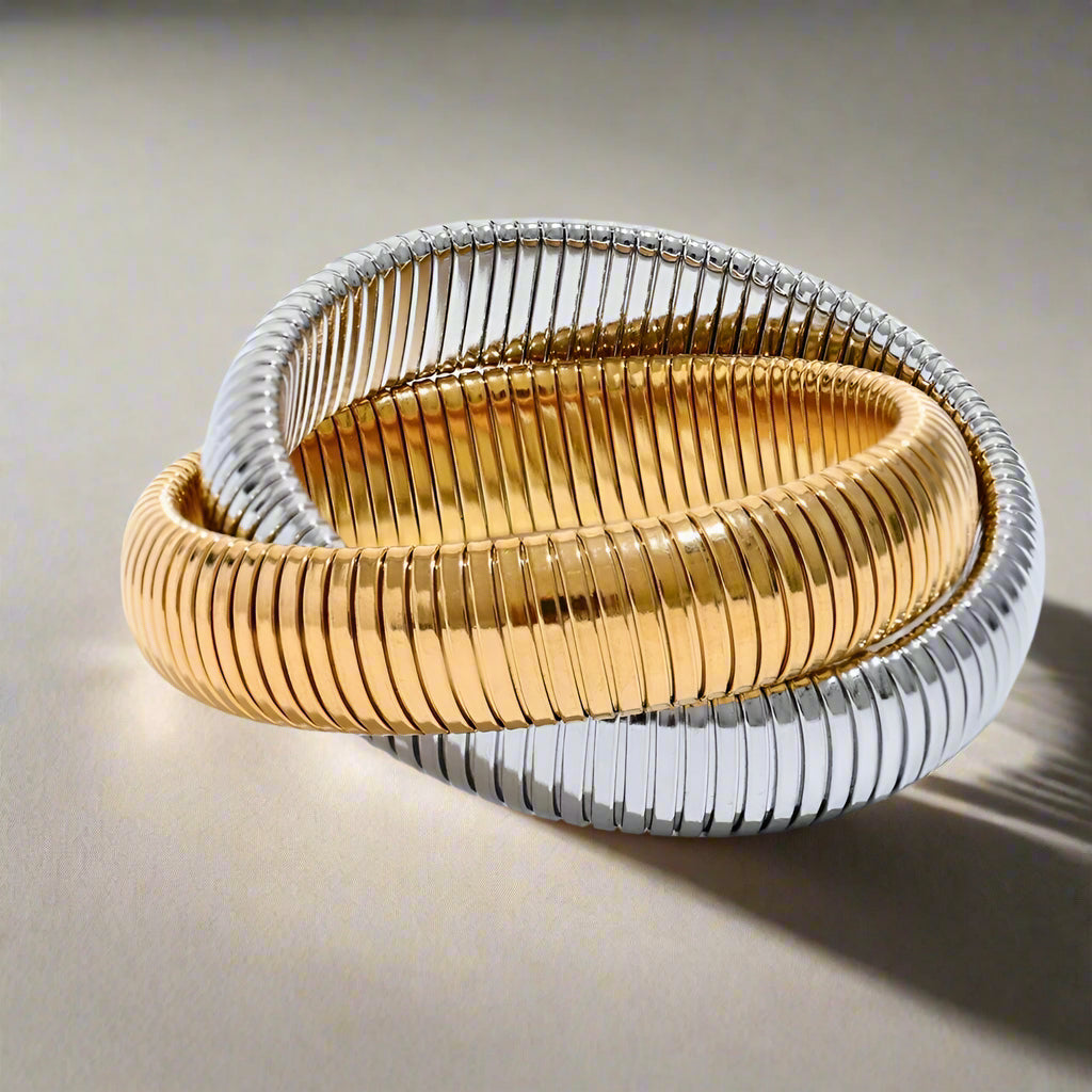 Two gold and silver bracelets stacked on a white background