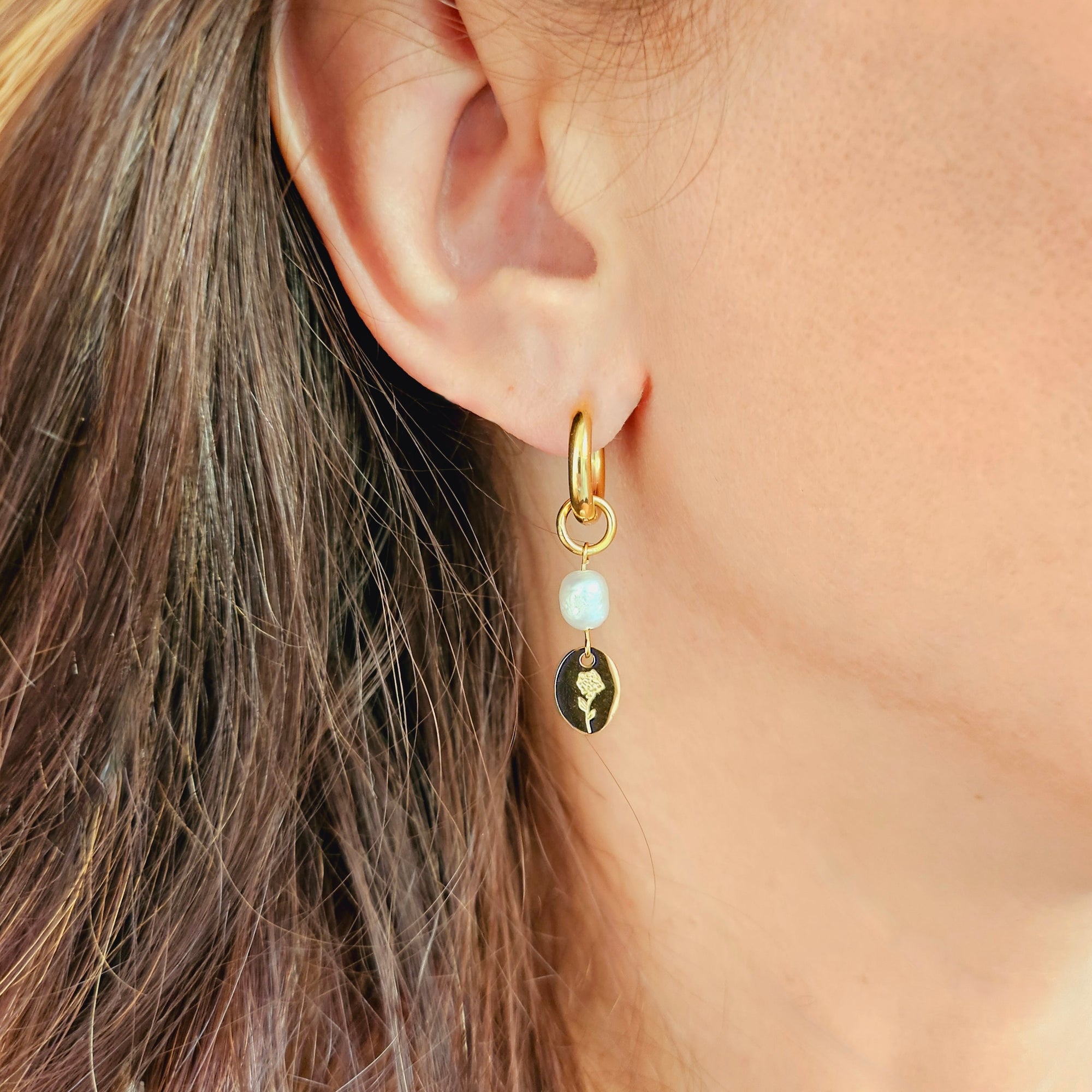 Hand-engraved charm earrings with freshwater pearl drops, worn on ear