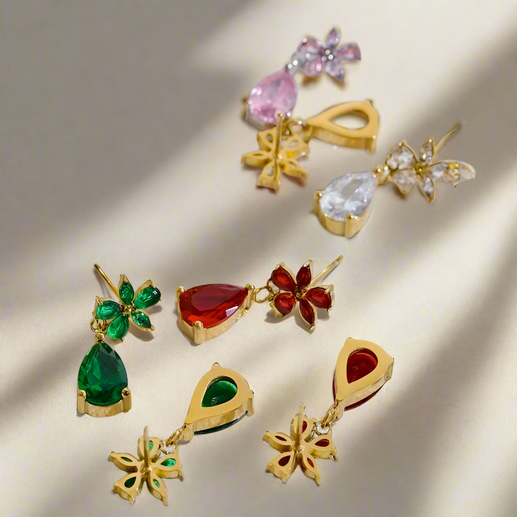 Gold earrings with gemstones on a textured white surface