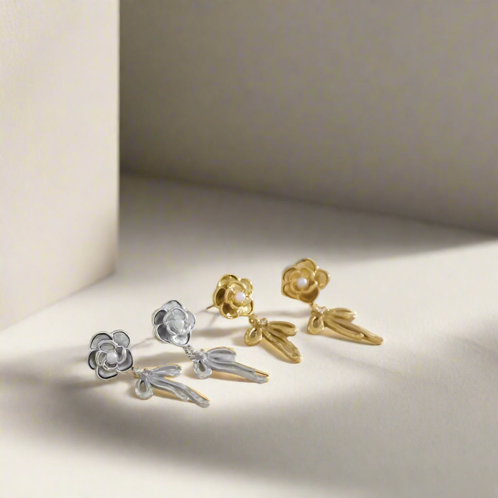 Pair of gold and silver floral earrings on a neutral background