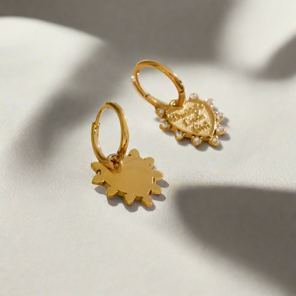 Gold heart-shaped earrings on a light fabric background