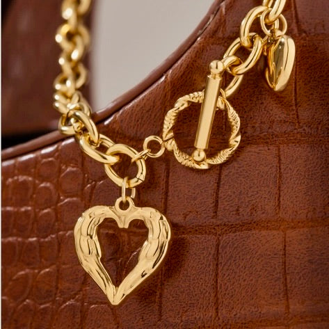 Gold heart chain necklace with toggle clasp styled on purse