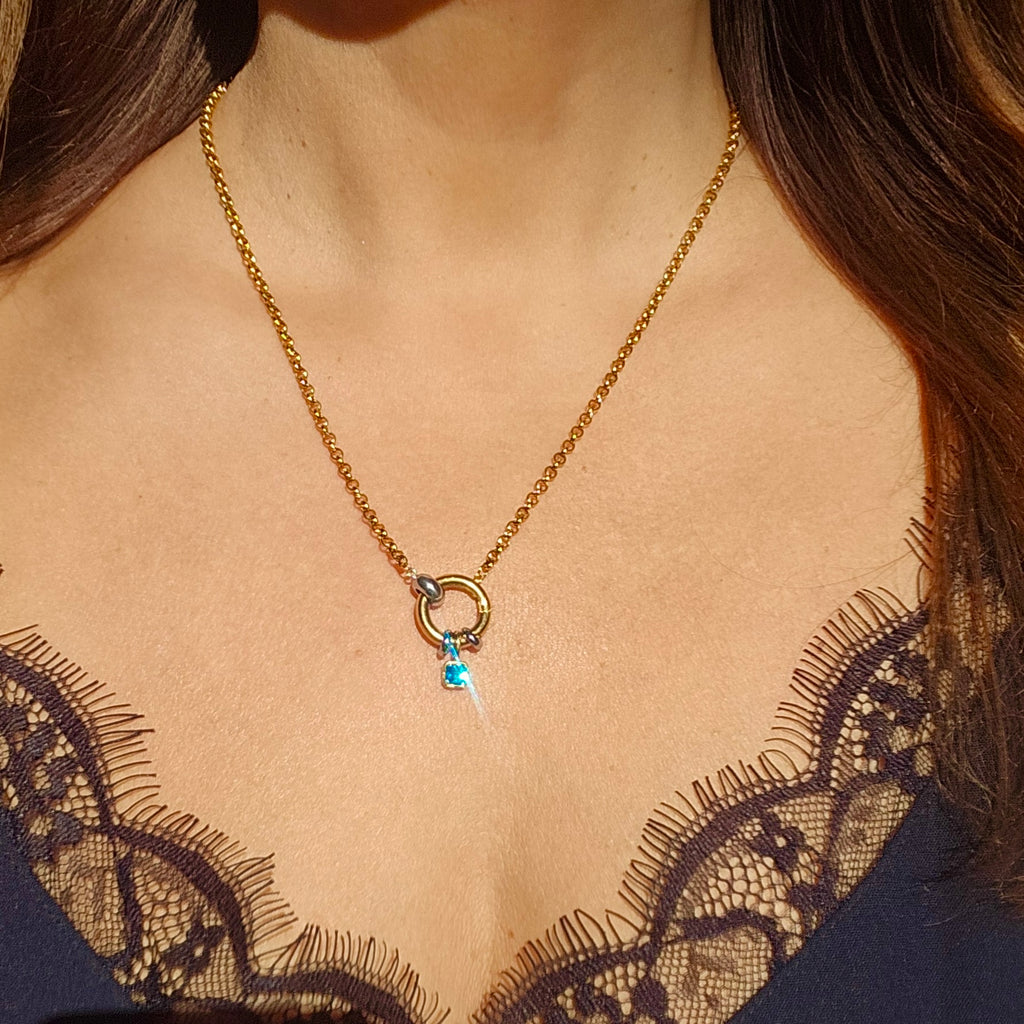 Gold pendant with colorful gemstones, styled on a woman