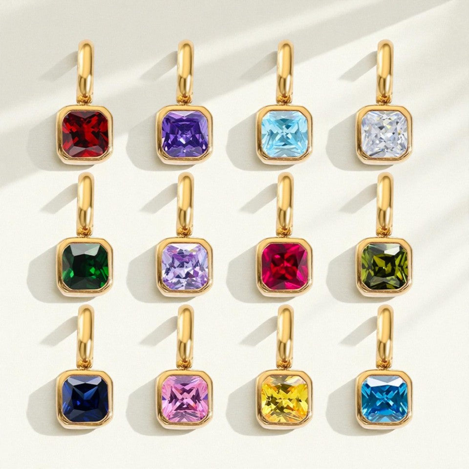 Gold pendants with colorful gemstones on a light background