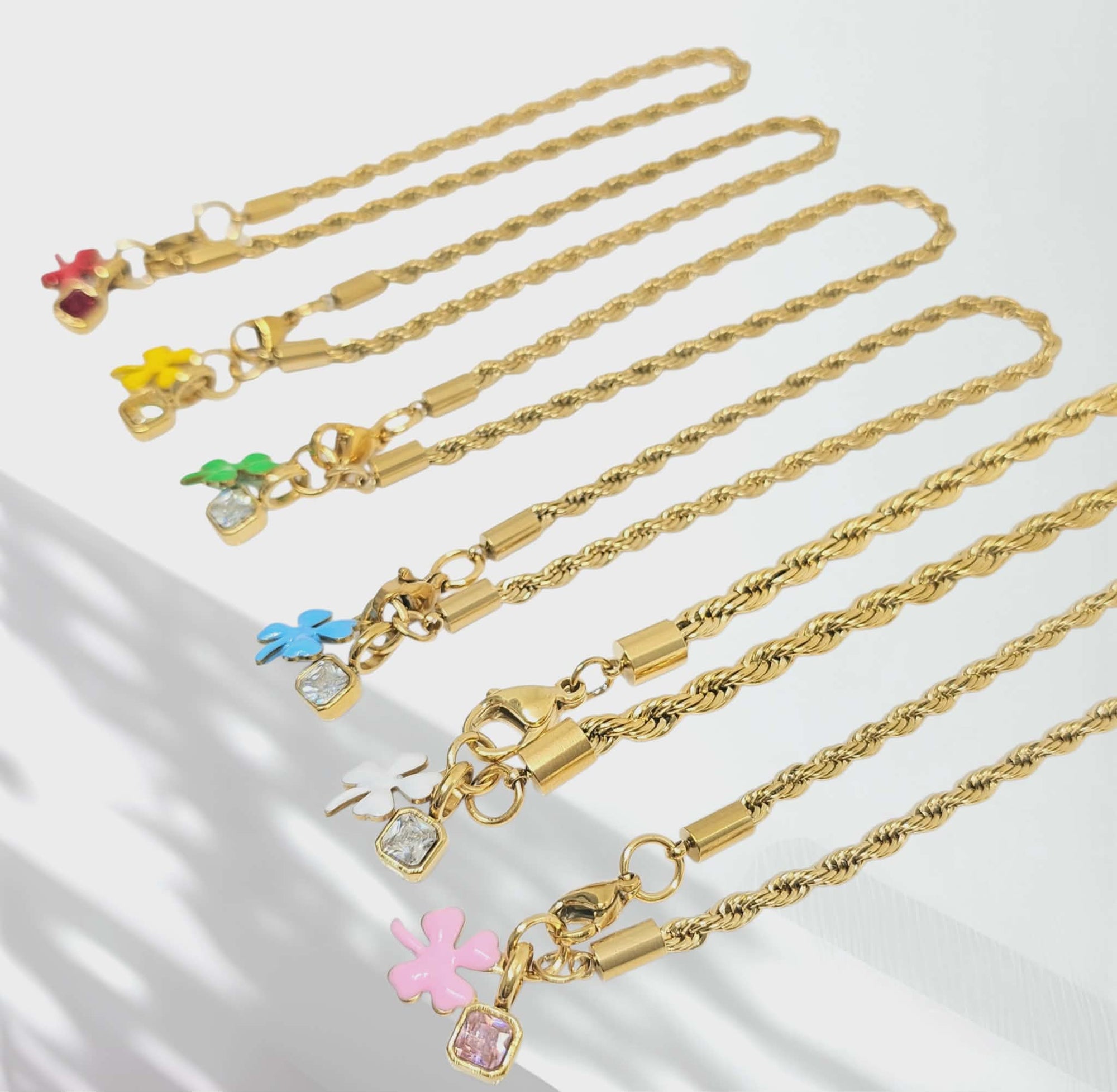 Gold necklaces with colorful flower charms on a white background