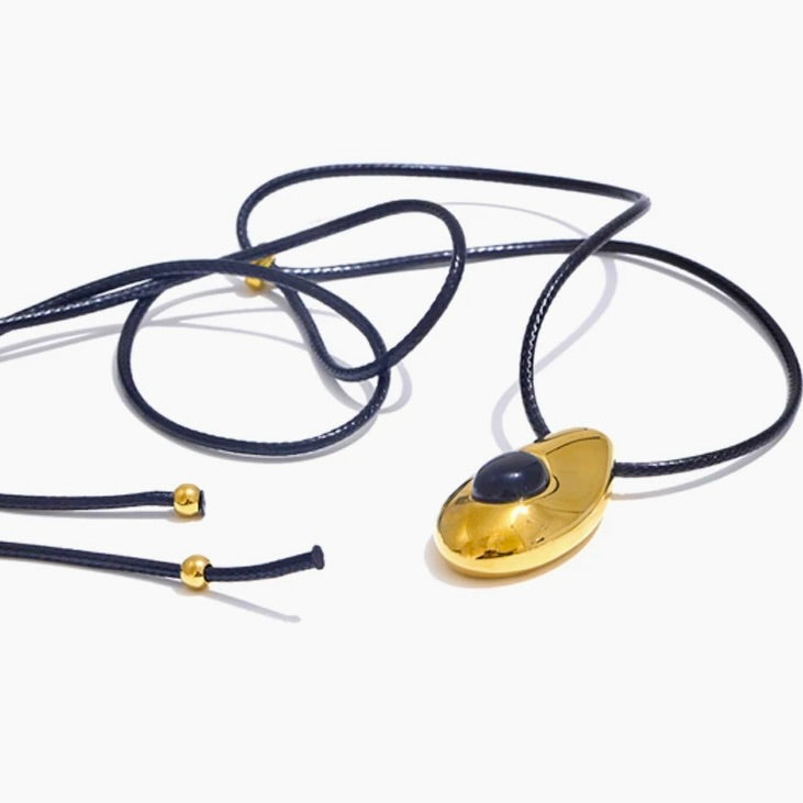 Gold pendant necklace with blue cord on a white background