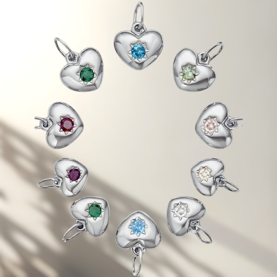 Heart-shaped silver charms with colorful gemstones on a light background