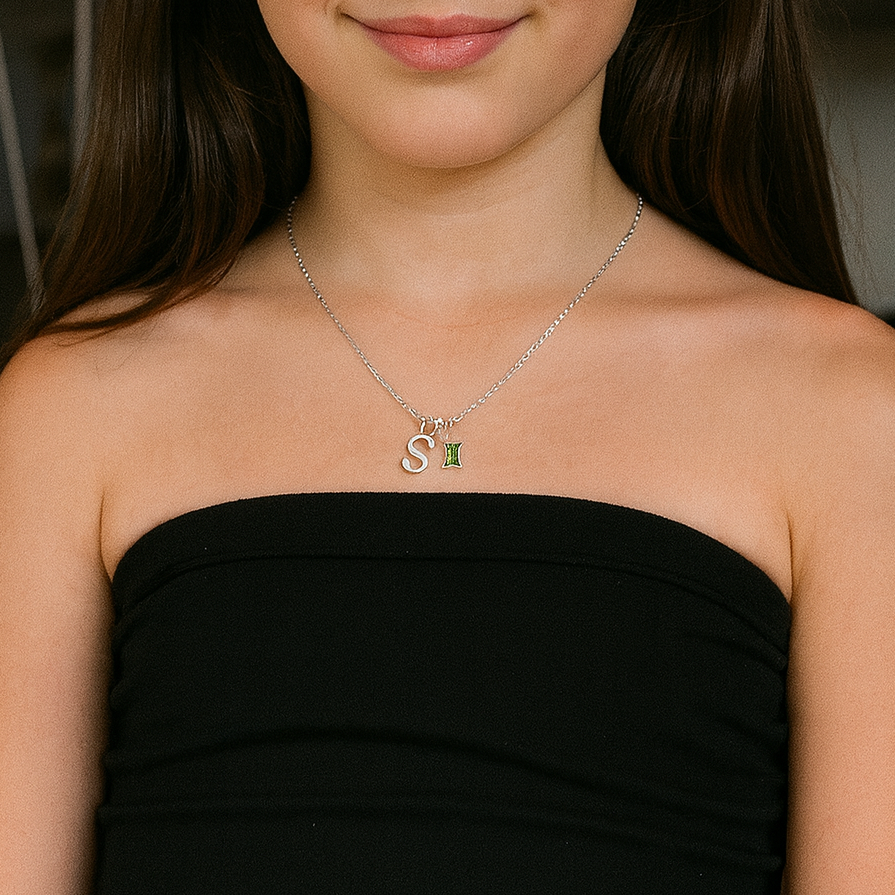 Young girl wearing a black strapless dress with a necklace indoors