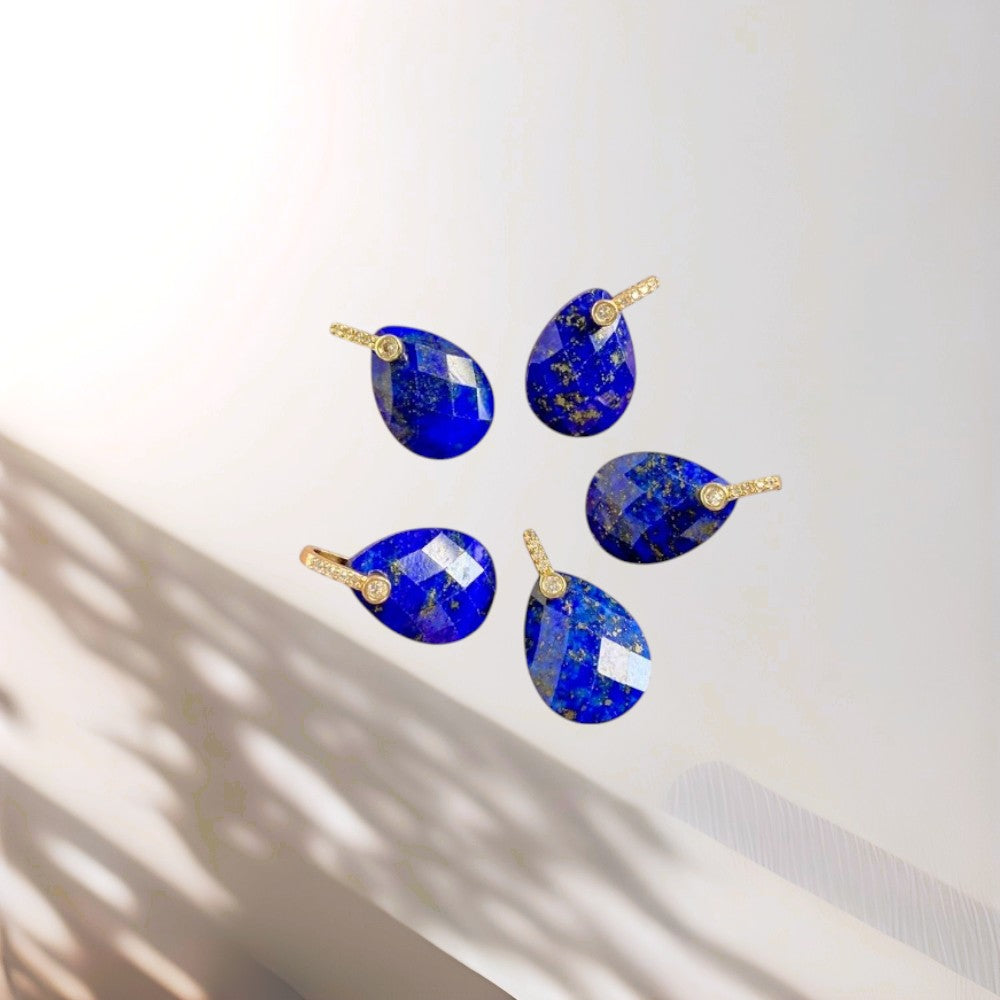 Set of blue teardrop-shaped earrings with gold accents on a white background