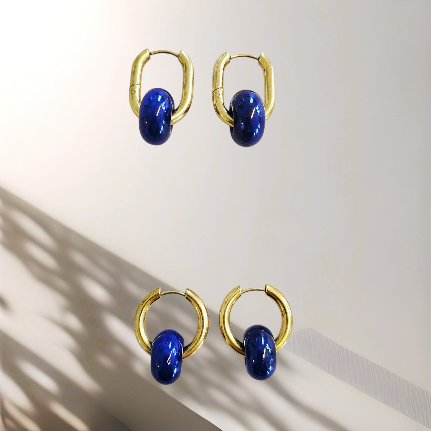 Gold hoop earrings with blue stones on a light background