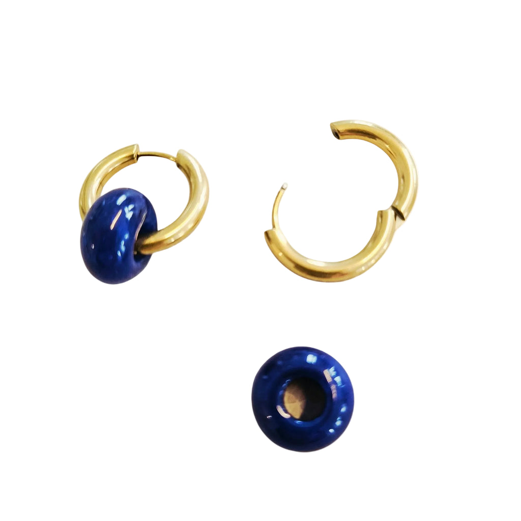 Pair of gold hoop earrings with blue spherical ends on a white background