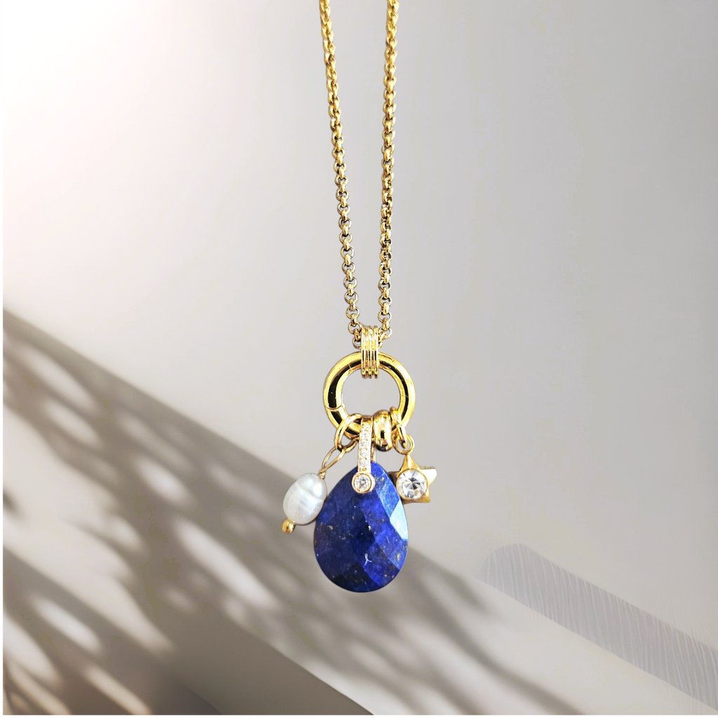 Gold necklace with blue pendant on a light background