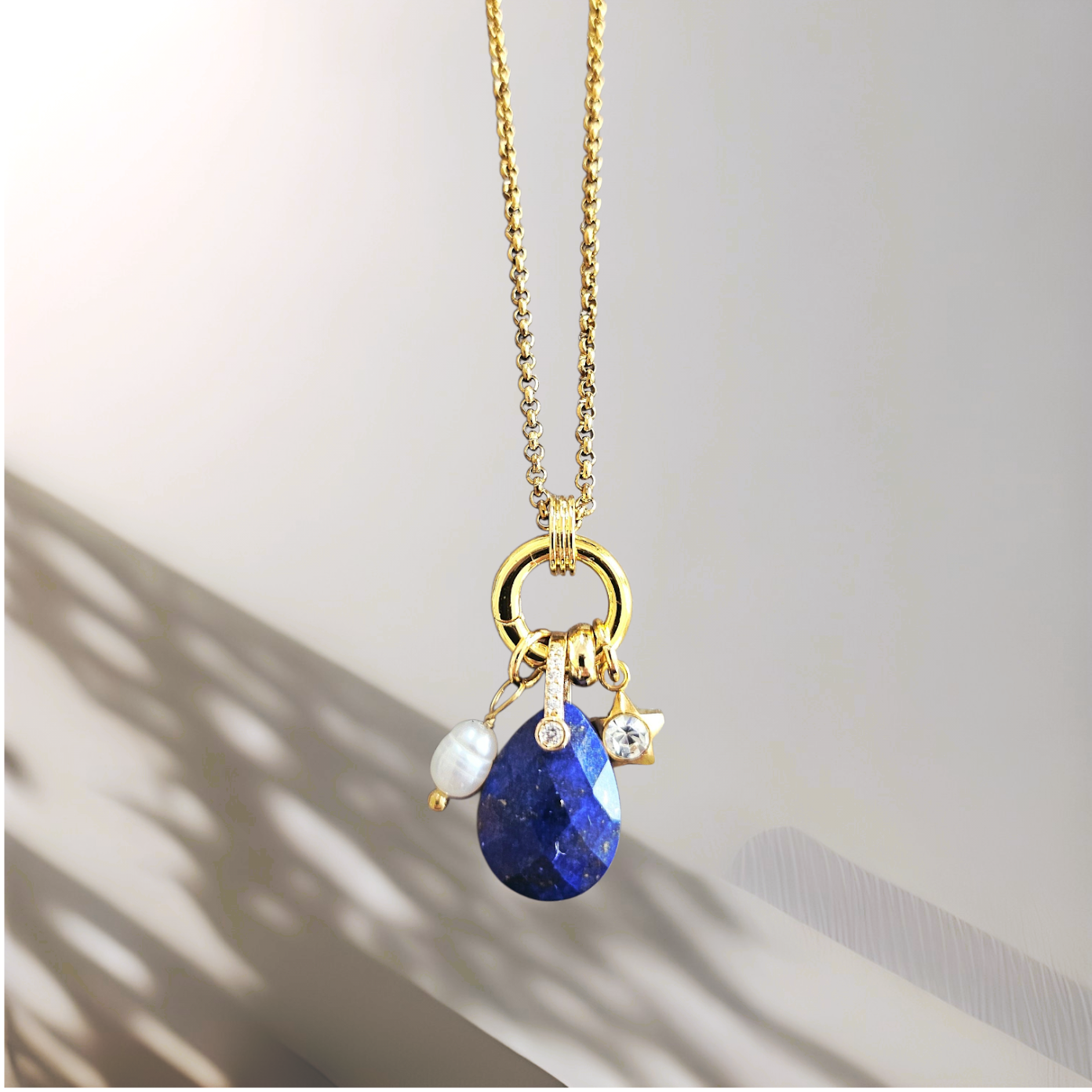 Gold necklace with blue pendant on a light background