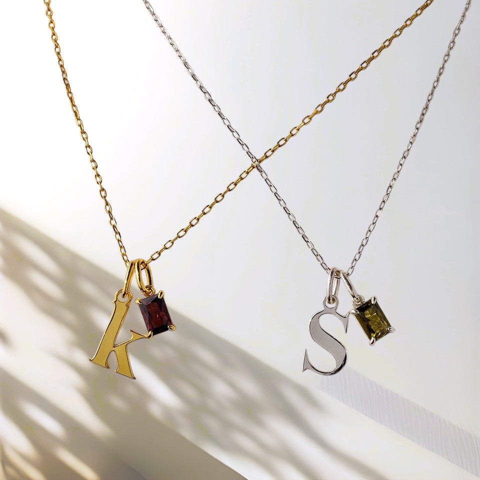 Two necklaces with letter pendants 'K' and 'S' on a light background