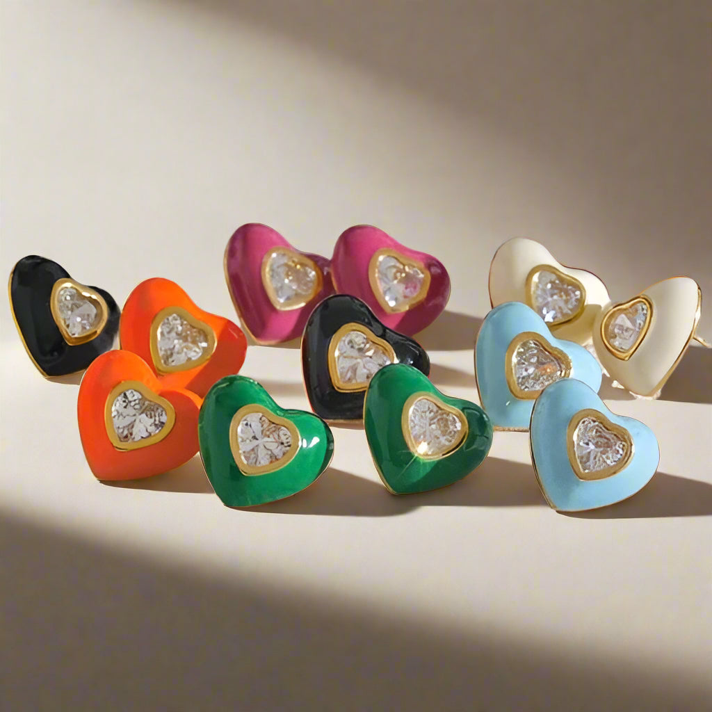 Colorful heart-shaped earrings with embedded stones on a beige background