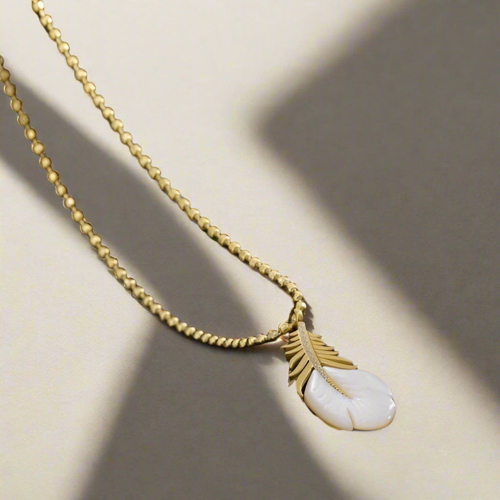 Necklace with a feather and shell pendant on a dark textured background