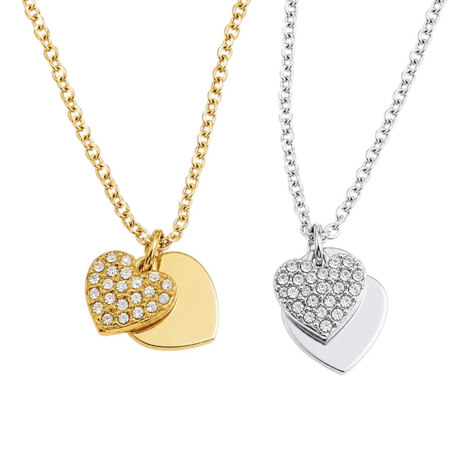 Two heart-shaped pendant necklaces on white backgrounds, one in yellow gold and one in silver, each featuring a pavé heart and a solid overlapping heart.