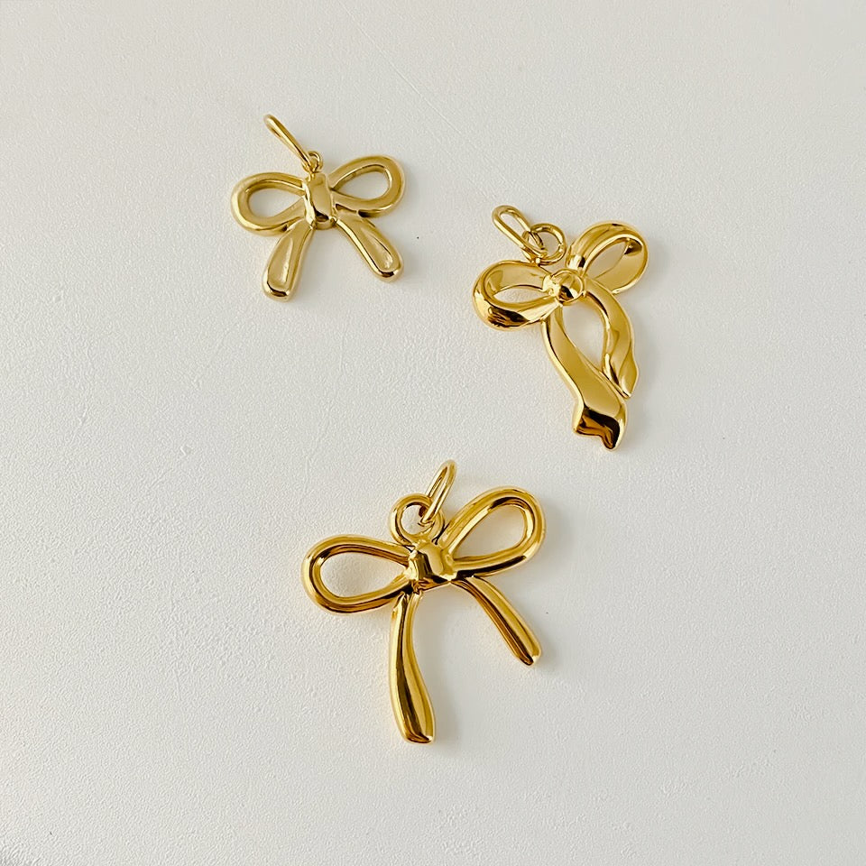 Three gold bow-shaped pendants on a light gray background
