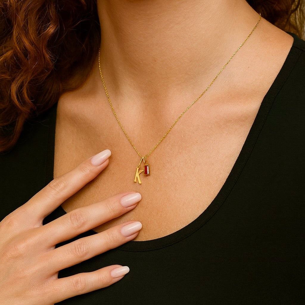 Gold necklace with a pendant on a person wearing a black top.