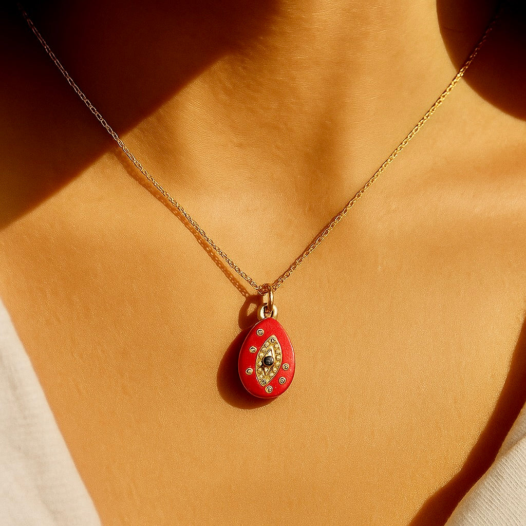 Red pendant necklace with gold chain on a person's neck
