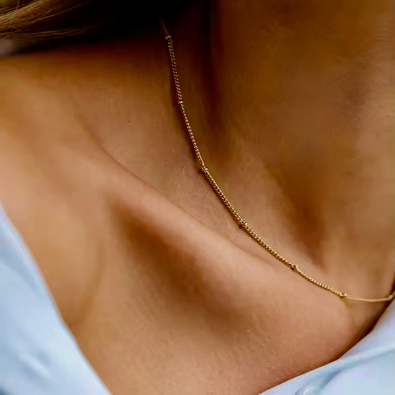 Gold satellite chain on a person wearing a light blue top