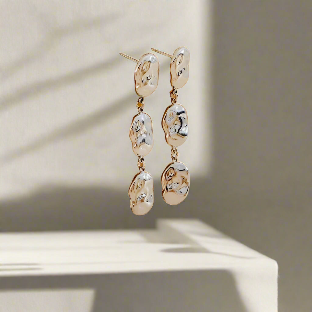 Close-up of waterproof hammered drop dangle earrings in gold, textured with a modern shine, designed for everyday and special occasions.