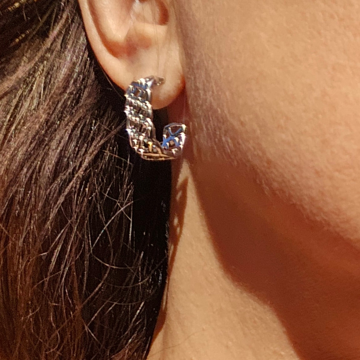 Close-up of a silver hoop earring worn by a person with dark hair.