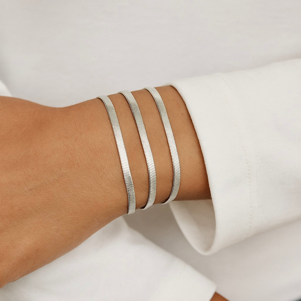 Silver bracelets on a wrist with a neutral background