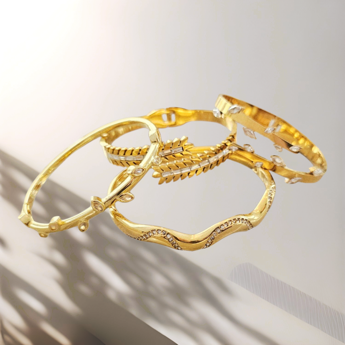 Three gold bangles with intricate designs on a light background