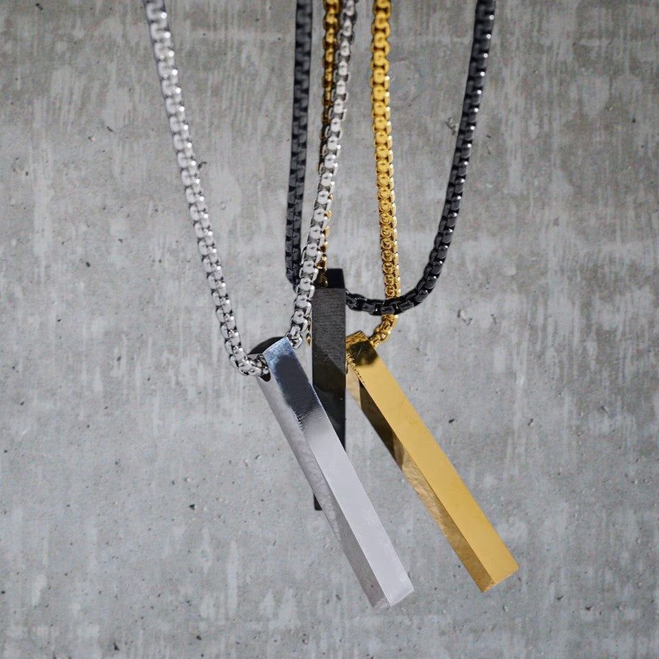 Three necklaces with different colored pendants on a concrete surface