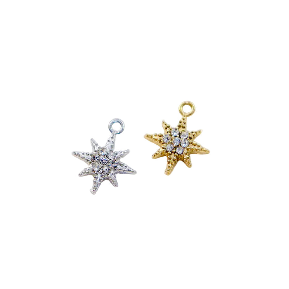 Two star-shaped charms, one silver and one gold, on a textured white background.