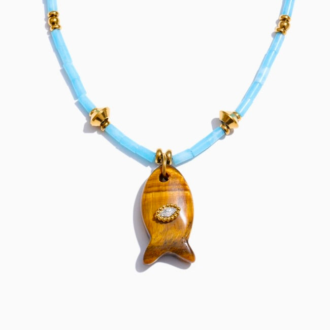 Necklace with a gold fish pendant on a light blue cord against a white background