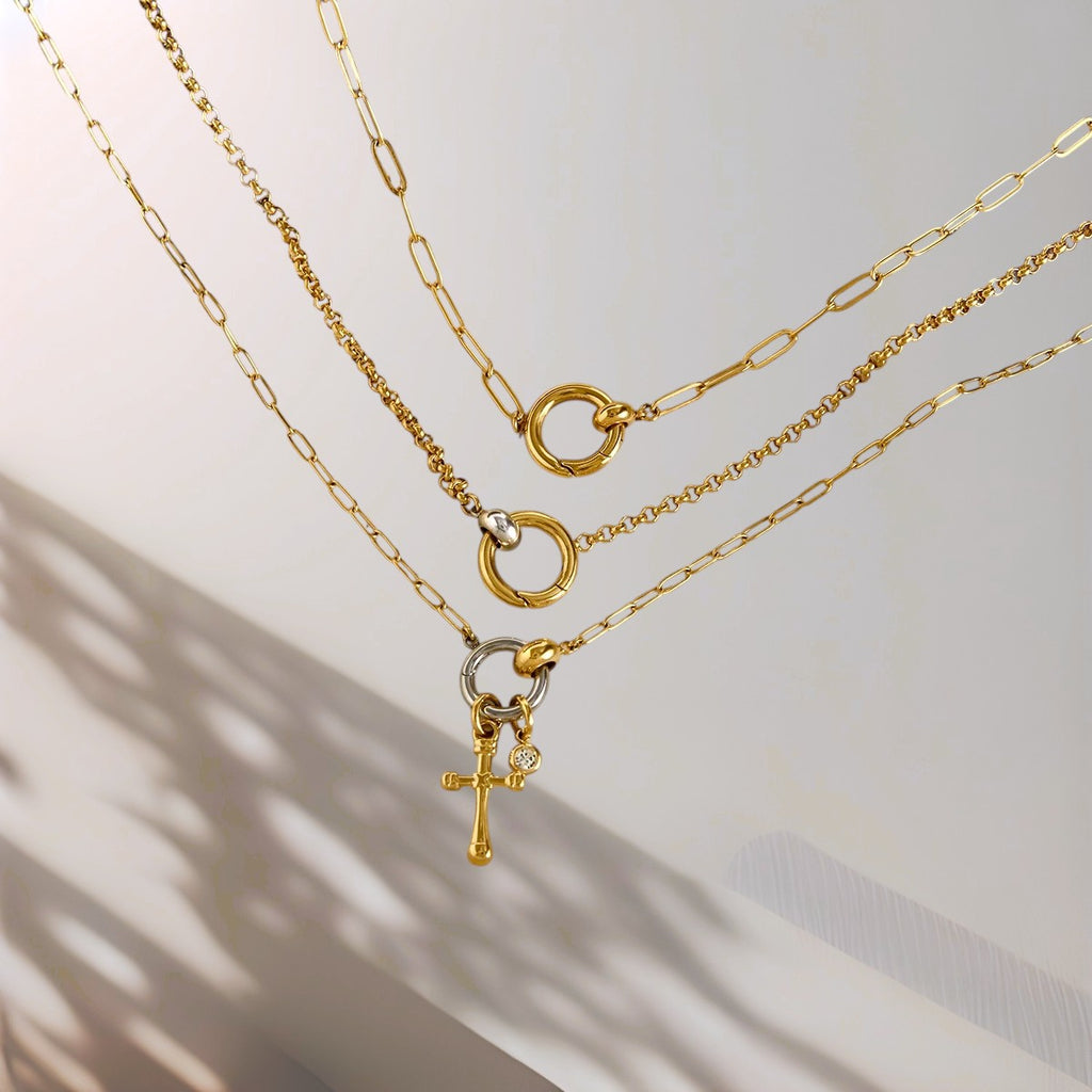 Three gold chain with various pendants on a light background
