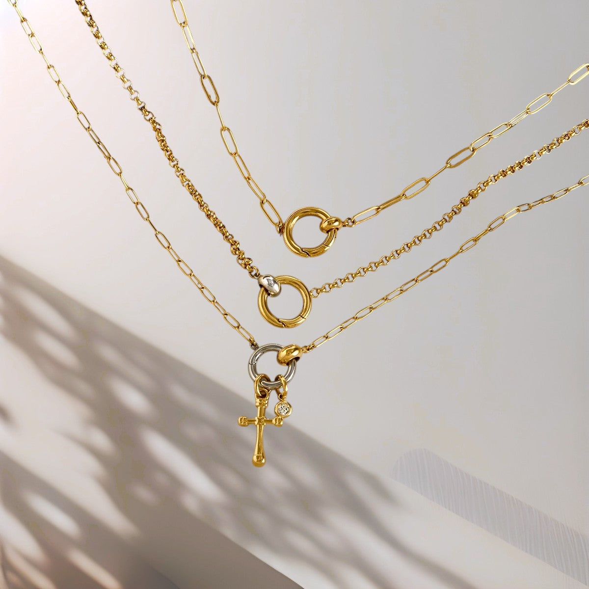Three gold chain with various pendants on a light background