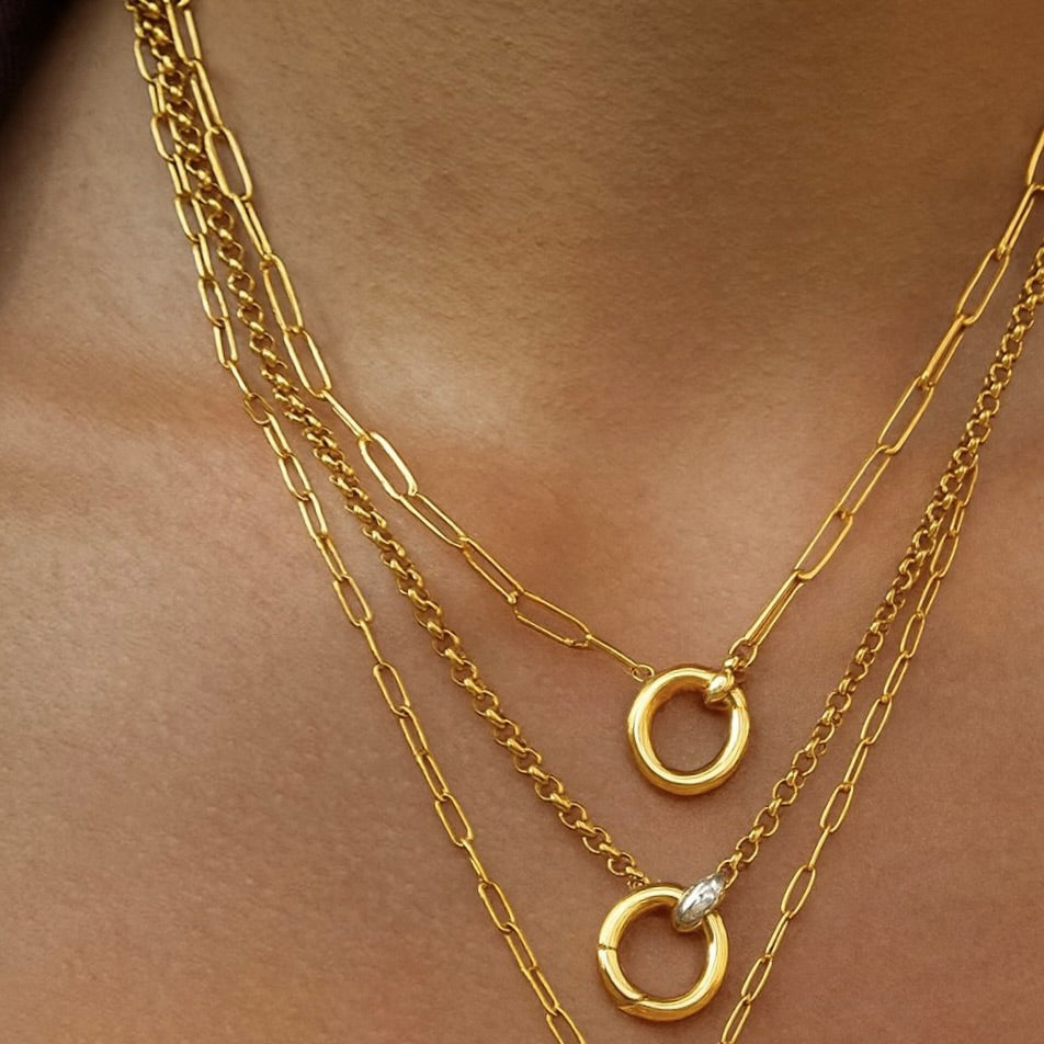 Gold chain necklaces with circular pendants on a skin-toned background