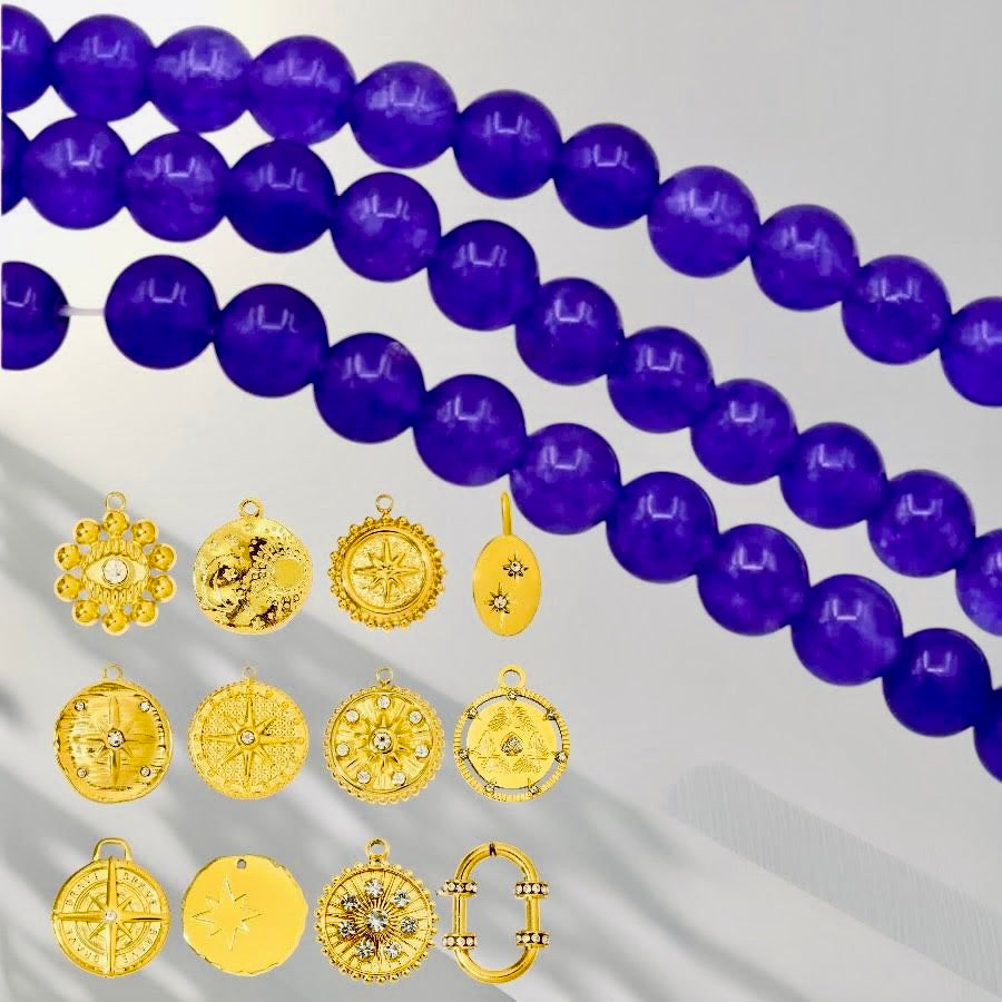 Purple round gemstone beads arranged diagonally with multiple gold-toned pendant charms displayed below on a light gray background.