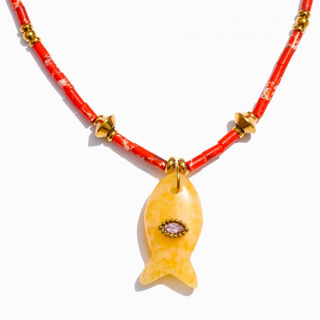 Necklace with a yellow fish pendant on a red beaded chain against a white background