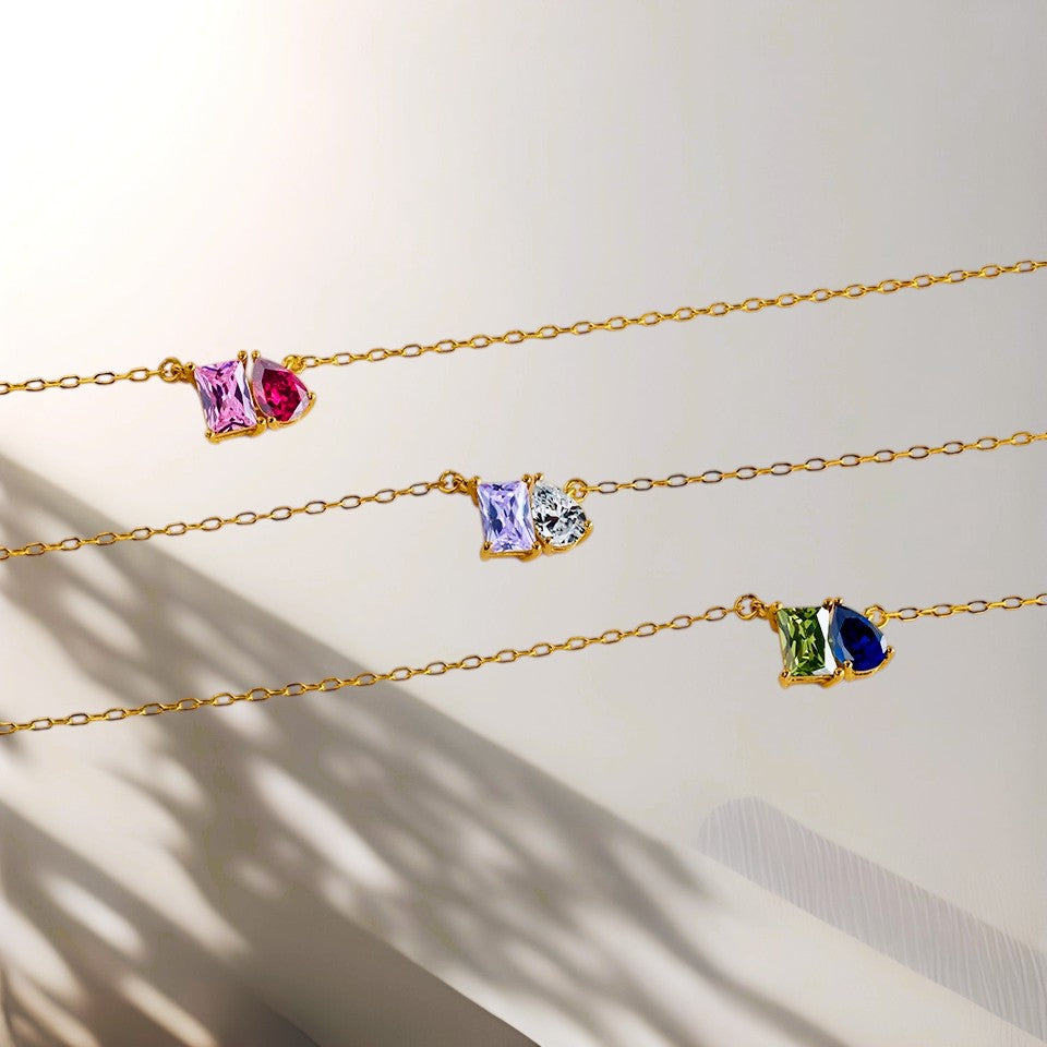 Three gold necklaces with colorful gemstones on a light background